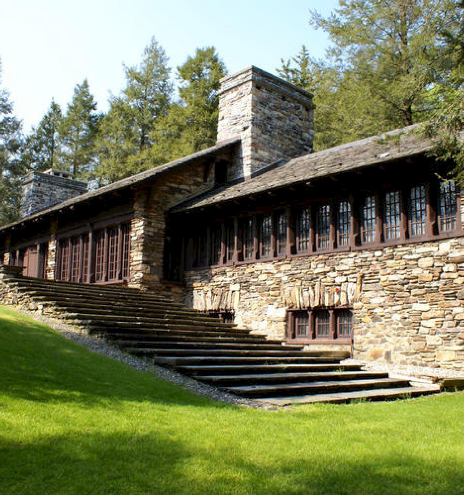 Stone building with large windows nestled in a lush forest setting.