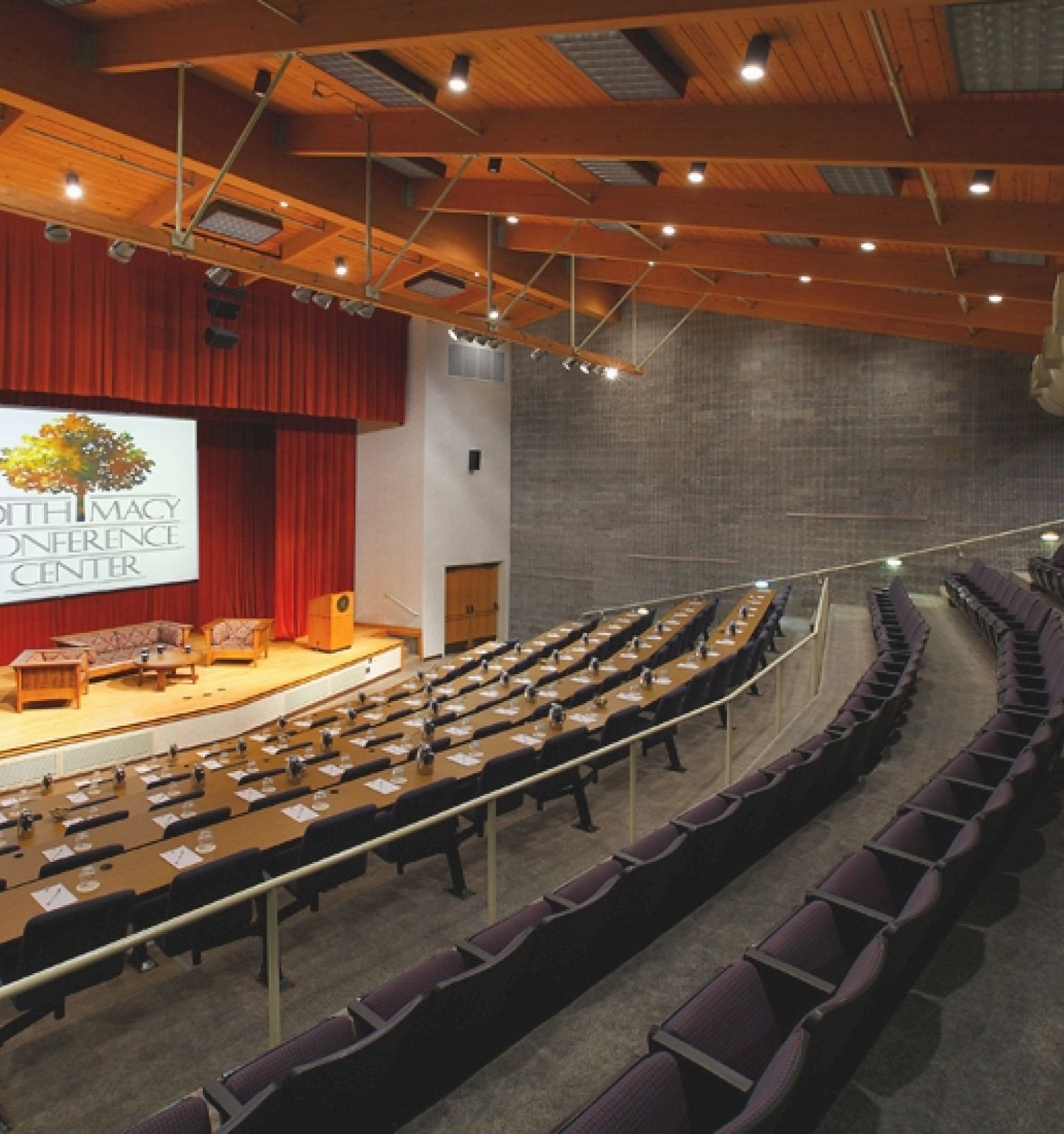 Auditorium with seats facing a stage and a projected screen.