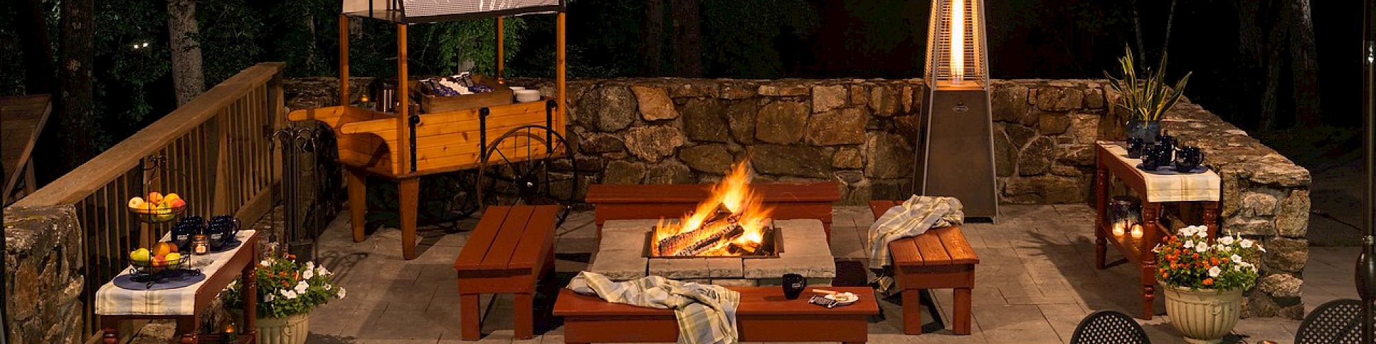 Outdoor patio with a fire pit, seating, and ambient lighting at night.