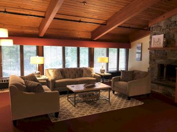 Cozy living room with sofa set, coffee table, fireplace, and wooden ceiling.