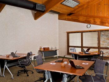 An office meeting room with tables, chairs, and papers scattered around.