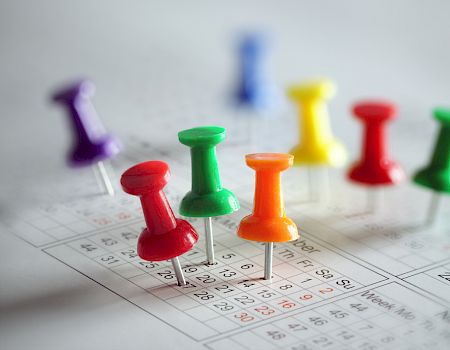 Colorful pushpins stuck on a calendar, signifying dates and events.