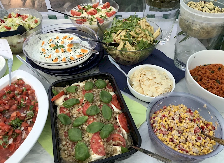 A variety of fresh salads and dips displayed on a table.