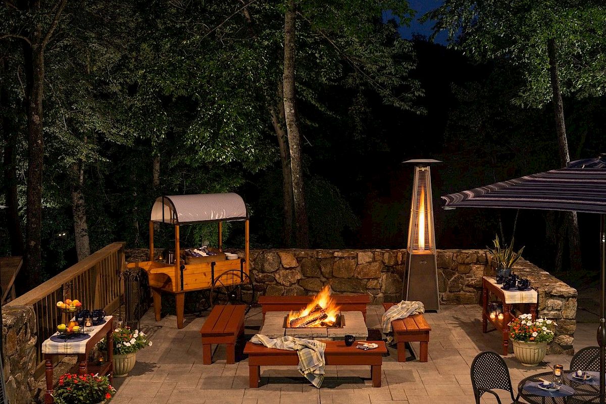 An outdoor patio with a fire pit, seating, and ambient lighting at night.