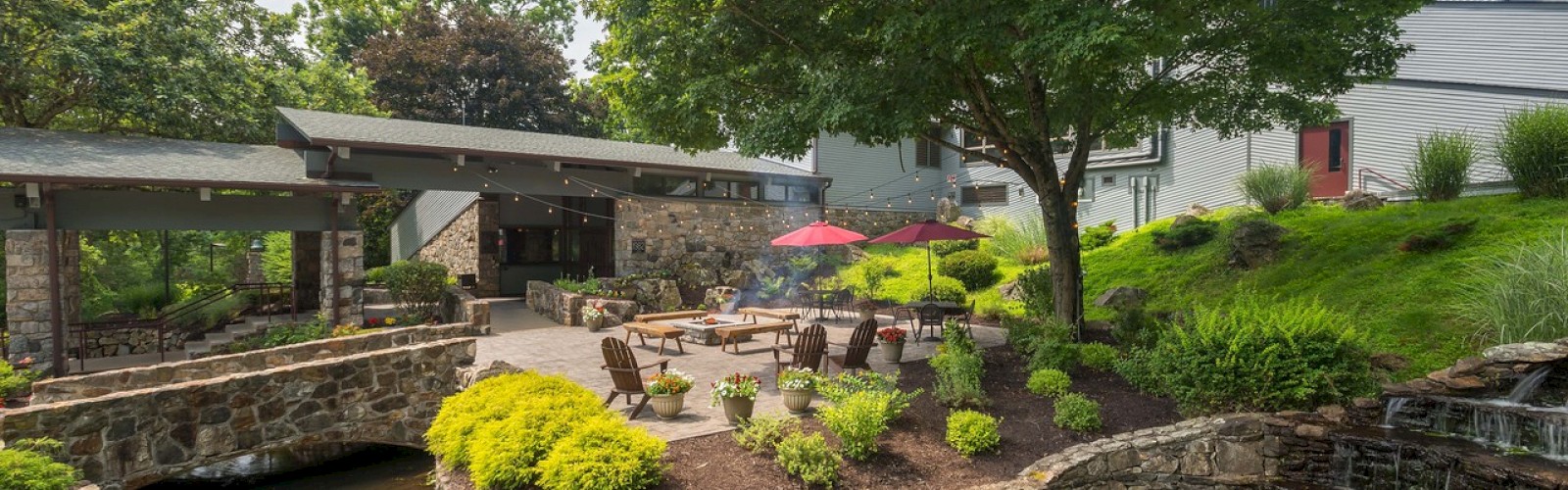 Tranquil garden with seating area, pond, greenery, and an umbrella.