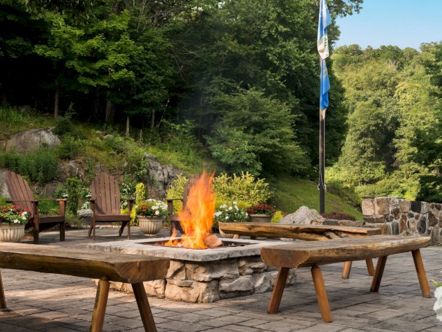 Outdoor seating with a fire pit, surrounded by nature and a flagpole.