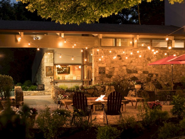Outdoor patio with lights, seating area, and a lit fire pit.