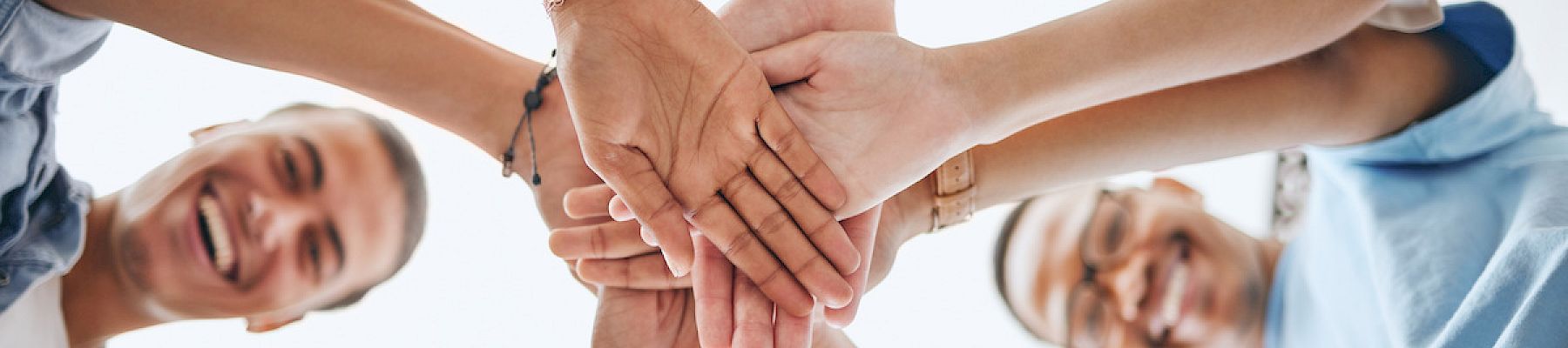 A group of people is stacking hands together in a sign of unity and teamwork.