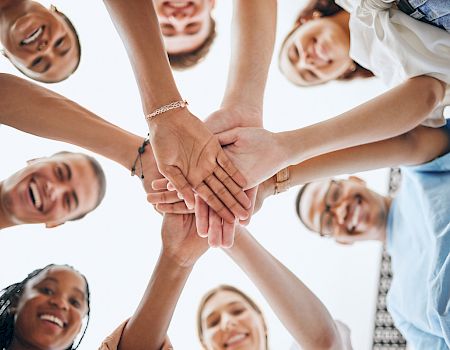 A group of people is stacking hands together in a sign of unity and teamwork.
